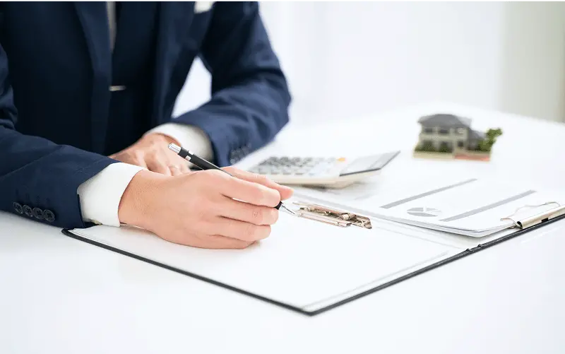 スーツを着た男性が書類を記入している写真